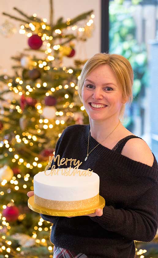 Vrouw met christmas cake voor kerstboom